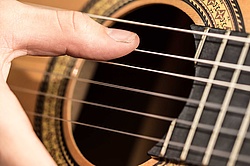 Spielhand am Schallloch einer Gitarre